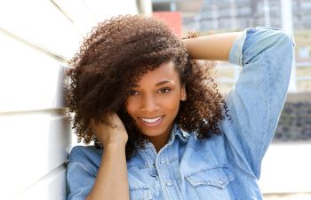 A joyful young Afro-American woman holding her arm up.